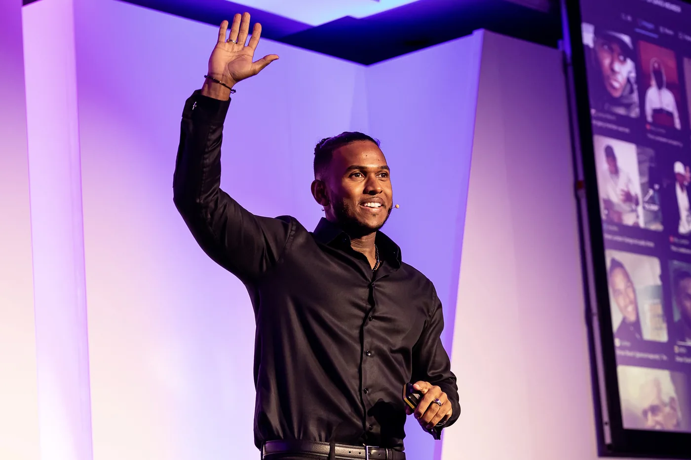 Omar Sharif on stage, hand raised, mid keynote