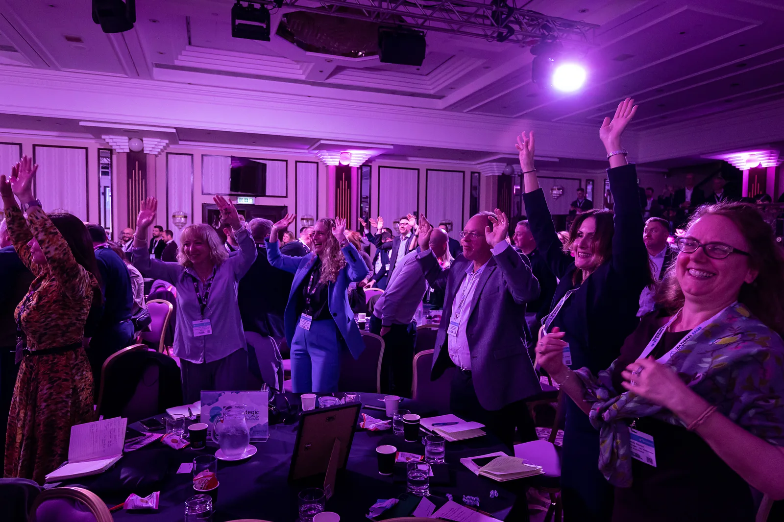 Delegates at the National Sales Conference standing with their hands in the air, laughing